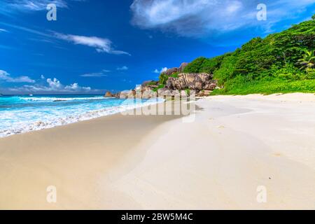 Carte postale paisible et parfaite de la plage des Seychelles à la Digue. La plage de sable blanc et la mer turquoise de Grand Anse sont accessibles par une route dans l' Banque D'Images