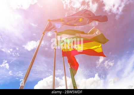 Drapeaux de l'Europe, de l'Andalousie, de Grenade et de l'Espagne, agitant dans un ciel nuageux. Fond ciel libre pour un espace de copie et un soleil éclatant. Banque D'Images