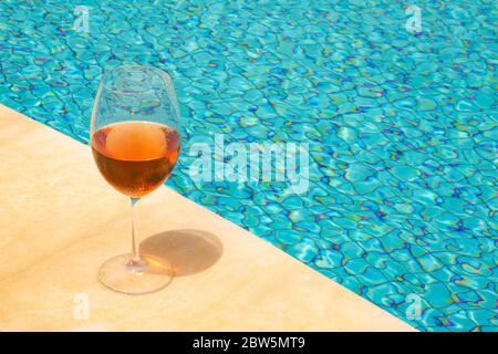 Verre de vin en bordure d'une piscine. Vin de rose dans un gobelet en verre. Concept de richesse. Banque D'Images