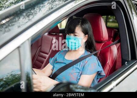 Femme dans un masque de protection conduisant une voiture sur la route Banque D'Images