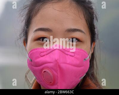 La jeune femme vietnamienne porte un masque facial rose avec valve respiratoire pendant la pandémie de 2019/20 du virus corona. Banque D'Images