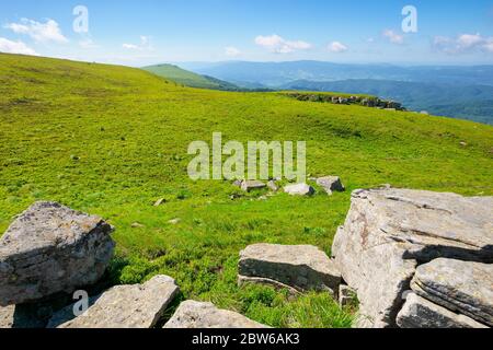 prairie de montagne en paysage d'été. ciel bleu avec des nuages moelleux. magnifique paysage d'été par une journée ensoleillée. rochers sur la pente au milieu de l'herbe. vue sur Banque D'Images