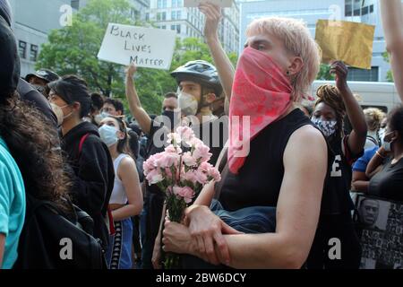 29 mai 2020, New York, New York, États-Unis : de grandes foules se sont emmenées dans les rues de New York pour protester contre la mort de George Floyd et des cas de brutalité policière pour la deuxième journée consécutive. Des centaines, à visage masqué, se sont rassemblées sans appliquer de distanciation sociale sur Foley Square devant la Cour de justice de Manhattan, criant leur colère et appelant le Conseil municipal à réintroduire et à passer un projet de loi de chokehold. Cette femme au visage masqué montre avec des fleurs dans les mains. La nuit, les manifestations à Brooklyn ont tourné à la violence, avec une douzaine d'officiers du NYPD blessés et au moins 120 arrestations. (Crédit IM Banque D'Images