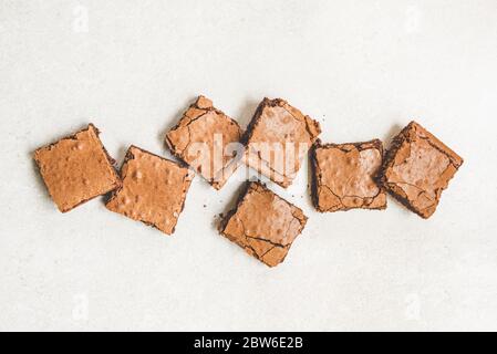 Vue de dessus du gâteau au brownie fraîchement cuit maison coupé en carrés sur fond rustique blanc. Banque D'Images