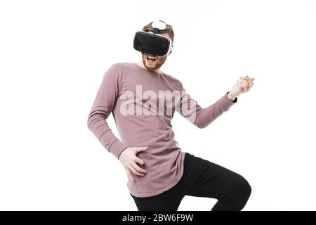 Portrait de garçon émotionnel en lunettes de réalité virtuelle jouant comme une guitare sur fond blanc. Jeune homme portant des lunettes de réalité visuelle isolées Banque D'Images