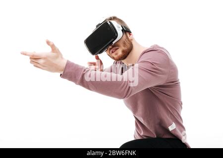 Portrait d'un garçon cool dans des lunettes de réalité virtuelle jouant dans un jeu de tir sur fond blanc. Jeune homme portant des lunettes de réalité visuelle isolées Banque D'Images