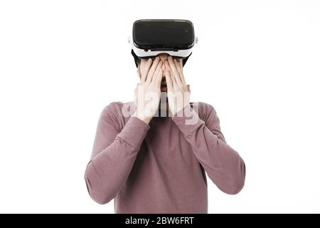 Portrait d'un jeune garçon fermant les yeux avec les mains portant des lunettes de réalité visuelle sur fond blanc. Homme jouant avec des lunettes de réalité virtuelle Banque D'Images