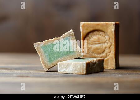 Bar et deux tranches de savon de Laurier biologique traditionnel alep sur fond de bois brun. Concept de traitement de la peau Banque D'Images