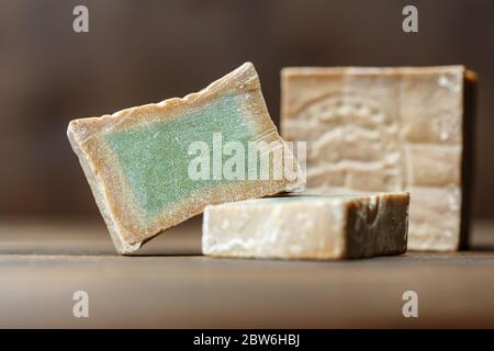 Bar et deux tranches de savon de Laurier biologique traditionnel alep sur fond de bois brun. Concept de traitement de la peau Banque D'Images