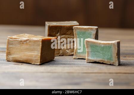 Deux barres et tranches de savon de Laurier biologique traditionnel alep sur fond de bois brun. Concept de traitement de la peau Banque D'Images