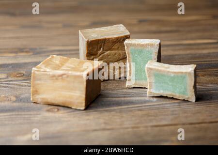 Deux barres et tranches de savon de Laurier biologique traditionnel alep sur fond de bois brun. Concept de traitement de la peau Banque D'Images