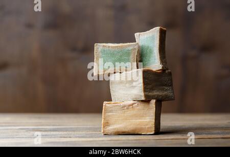 Deux barres et tranches de savon de Laurier biologique traditionnel alep sur fond de bois brun. Concept de traitement de la peau Banque D'Images