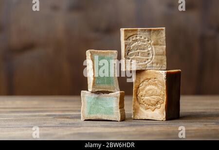 Deux barres et tranches de savon de Laurier biologique traditionnel alep sur fond de bois brun. Concept de traitement de la peau Banque D'Images