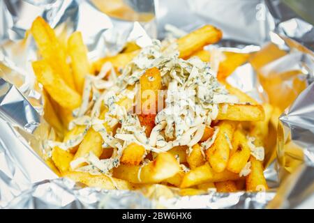 Frites au fromage bleu servies dans du papier aluminium à emporter.plat chaud livré dans de l'aluminium.frites frites frites frites pour repas légers Banque D'Images