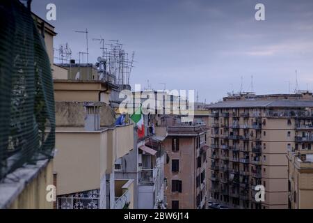 Un homme sur son balcon avec un grand drapeau italien pendant l'épidémie de COVID-19 à Rome, Italie Banque D'Images