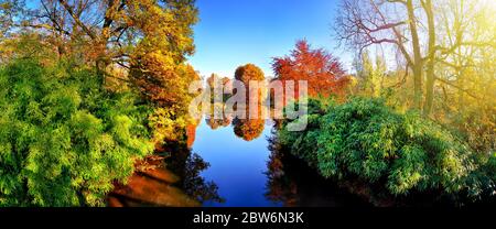 Flore colorée autour d'un lac bleu dans un parc en automne, avec des feuillages rouges, verts et jaunes, beau temps et soleil, un paysage panoramique Banque D'Images