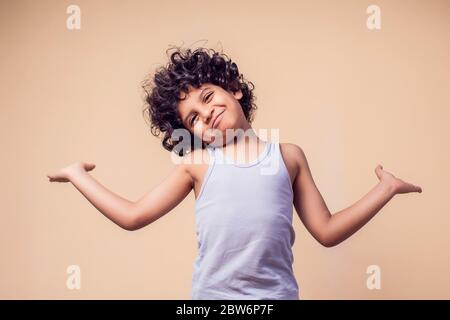 Un portrait d'un garçon avec des cheveux bouclés montrant le geste de doute. Enfants et émotions concept Banque D'Images