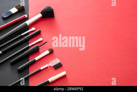 Make up pinceaux set contre fond rouge et noir, vue de dessus. Outils professionnels pour maquillage et art, salon de beauté, concept de cosmétiques Banque D'Images