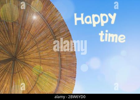 Le soleil brille à travers le parapluie de bambou. Toile de fond de toit en chaume avec l'inscription Happy Time. Copier l'espace. Vue de Straw Beach parasol depuis Abov Banque D'Images