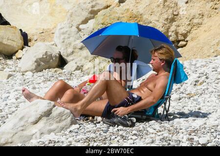 Lulworth Cove, Dorset, Royaume-Uni. 30 mai 2020. Météo Royaume-Uni. Un couple se prélassant sous le soleil sur la plage du village Lulworth Cove à Dorset qui est occupé avec des familles et des baigneurs de soleil sur une matinée de soleil brûlant. Crédit photo : Graham Hunt/Alay Live News Banque D'Images