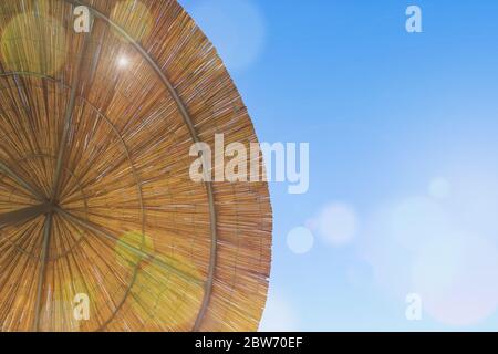 Le soleil brille à travers le parapluie de bambou. Toile de fond du toit de chaume, foin ou herbe sèche. Vue du haut du parasol de la plage de paille. Banque D'Images