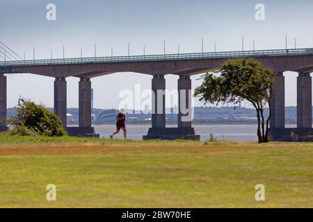 Un homme court le long du chemin le long de l'estuaire de la rivière Severn qui surplombe le pont du Prince de Galles Banque D'Images