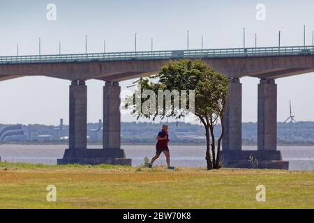 Un homme court le long du chemin le long de l'estuaire de la rivière Severn qui surplombe le pont du Prince de Galles Banque D'Images