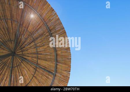 Le soleil brille à travers le parapluie de bambou. Toile de fond du toit de chaume, foin ou herbe sèche. Vue du haut du parasol de la plage de paille. Banque D'Images