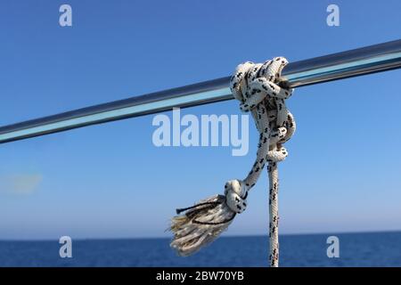 Rampe de bateau en acier inoxydable de détail de point de marine. Marin Fender Knot autour de Boat Lee. Corde à nœud marin en gros plan sur bateau à voile Banque D'Images