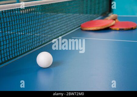 Raquettes pour le tennis de table de couleur rouge et une balle sur une table de tennis Banque D'Images