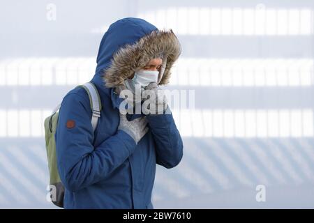 Malade jeune homme ayant un rhume, se sentir mal, éternuer, tousser et porter un masque médical, à l'extérieur. Bronchite, maladie, épidémie de grippe Banque D'Images