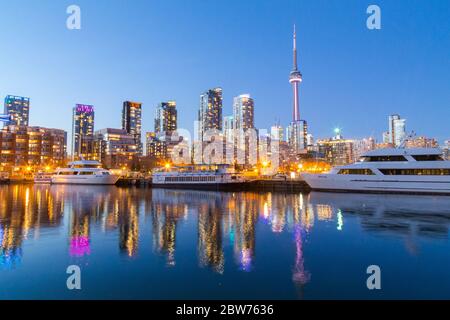 TORONTO, CANADA - 16 AVRIL 2015 : vue sur le centre-ville de Toronto au crépuscule, avec des édifices, des condos, la Tour CN et des bateaux. Banque D'Images