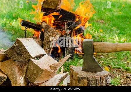 Hache et bois de chauffage sur fond de feu de camp. Banque D'Images