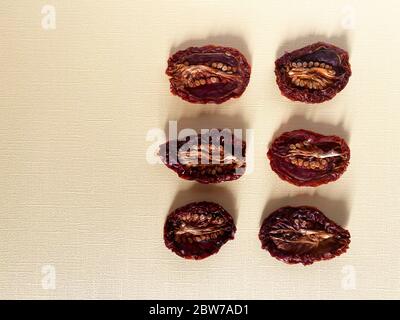 Tomates séchées ou séchées en deux moitiés, vue de dessus, différentes formes et tailles, graines en haut. Fond beige, couleurs naturelles Banque D'Images