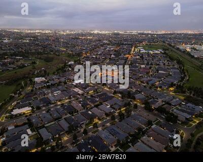 Vue aérienne de nouvelles maisons construites dans de nouvelles banlieues expansion urbaine rabais du gouvernement en soirée avec des parcs et lumières de ville Melbourne Victoria Australie Banque D'Images