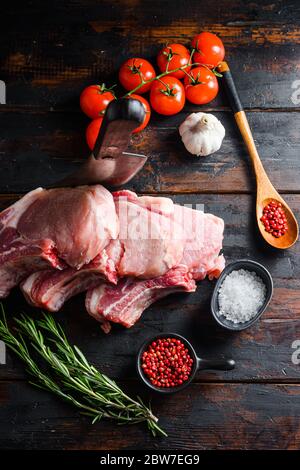 Côtelettes de porc bio de ferme biologique avec épices: Poivre, sel, feuille de Laurier. Boucher le couteau de la cale dans la table en bois sur bois rustique et métal backgroun de nourriture Banque D'Images