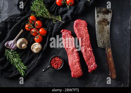 Ensemble cru de viande biologique coupée de denver avec romarin de légumes et autres ingrédients près de boucher couteau à viande pour barbecue ou griller sur le dos de pierre noire Banque D'Images