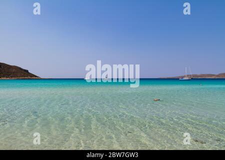 Baie de Simos à Elafonissos, Grèce du Sud. Un paysage paisible avec de l'eau turquoise et du ciel bleu. Quelques voiliers à l'horizon. Banque D'Images