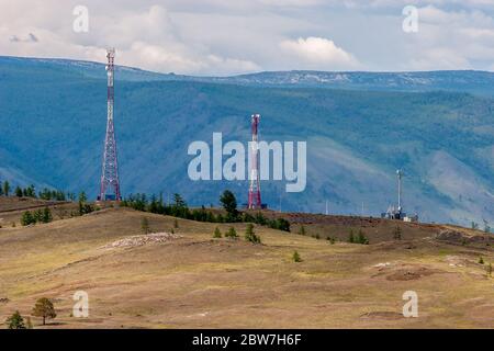 Antennes de tours de cellules avec des émetteurs debout sur les collines en arrière-plan des montagnes. Nuageux. Horizontale. Banque D'Images