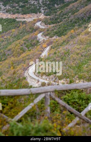 Route vide de montagne sinueuse, région de Xanthi, nord de la Grèce. Vue en grand angle, journée de brume de fin d'automne, photographie de voyage. Clôture en bois floue au premier plan Banque D'Images