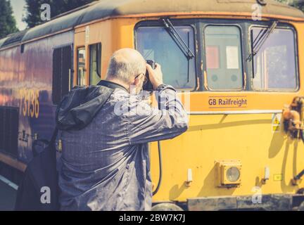 Vue arrière des fervents en train d'anorak photographiant la locomotive diesel britannique d'époque au soleil de printemps, Severn Valley Railway. Banque D'Images