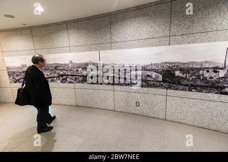 Homme regardant l'image d'une ville bombardée, à l'intérieur du National Peace Memorial Hall d'Hiroshima, Japon Banque D'Images