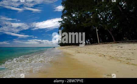 FLIC en FLAC/MAURICE - 20 AOÛT 2018: Les gens dans une journée ensoleillée marchant sur la plage publique de Flic en Flac avec des arbres tropicaux sur le bord de l'Océan Indien Banque D'Images