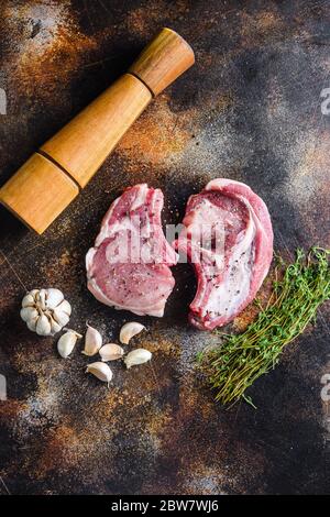 placez les steaks de porc hache bio sur du bois de fond sombre et de l'acier rustique, vue rapprochée verticale du dessus. Banque D'Images