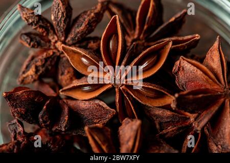 Photo macro d'anis étoilé sec de couleur brune dans un bol en verre utilisé pour préparer du vin chaud ou des desserts assaisonnés et des fruits confits Banque D'Images