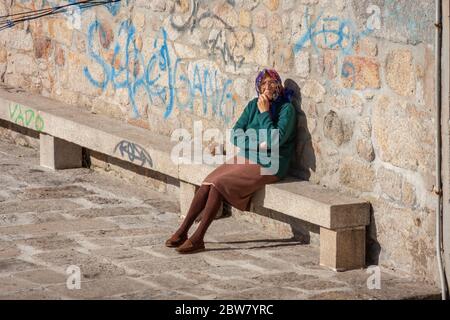 Une femme âgée assise sur le banc à l'extérieur de sa maison à Porto, Portugal Banque D'Images