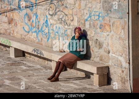 Une femme âgée assise sur le banc à l'extérieur de sa maison à Porto, Portugal Banque D'Images