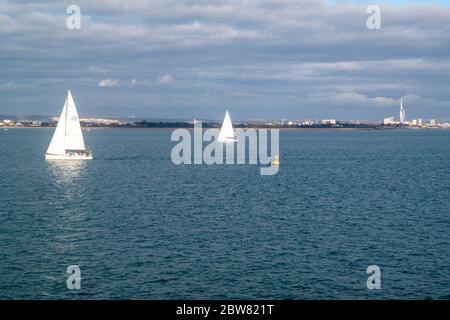 Vue sur deux yachts à voile sur le Solent, dans un après-midi frais de novembre avec Portsmouth en arrière-plan Banque D'Images