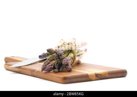 Bouquet d'asperges fraîchement cueillies, nouées avec une ficelle rustique sur un panneau en bois photographié sur fond blanc avec espace de copie. Banque D'Images