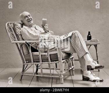 1930 HOMME SENIOR DANS LE PANTALON RAYÉ SPECTATEUR CHAUSSURES DÉTENTE DANS LE ROTIN CHAISE LECTURE MAGAZINE BOIRE DE LA BIÈRE REGARDER L'APPAREIL-PHOTO - F1349 HAR001 HARS RIRE HEUREUX JOIE DE STYLE DE VIE SATISFACTION AÎNÉ PATIO STUDIO PRISE DE VUE SAINTETÉ MAISON VIE LUXUEUSE COPIE ESPACE PLEINE LONGUEUR PERSONNES HOMMES RETRAITE HOMME SENIOR HOMME SENIOR B&W CONTACT VISUEL RRETIATTAN REHAPPENESS OLD AGE OLDSTERS GAIETÉ OLDSTER BOISSON LOISIRS STYLES PANTALON FIERTÉ FLUIDE SUR LES SOURIRES ANCIENS SPECTATEUR JOYEUX ÉLÉGANT DEUX TONS BREWSKI MODES DÉTENTE BOISSONS NOIR ET BLANC CAUCASIEN ETHNICITÉ HAR001 ANCIEN MODE Banque D'Images